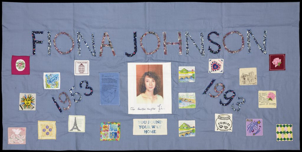 Photo of a quilt panel. the background is light blue. There is a photo of a younger white woman with curly auburn hair and the dates 1953 - 1993.